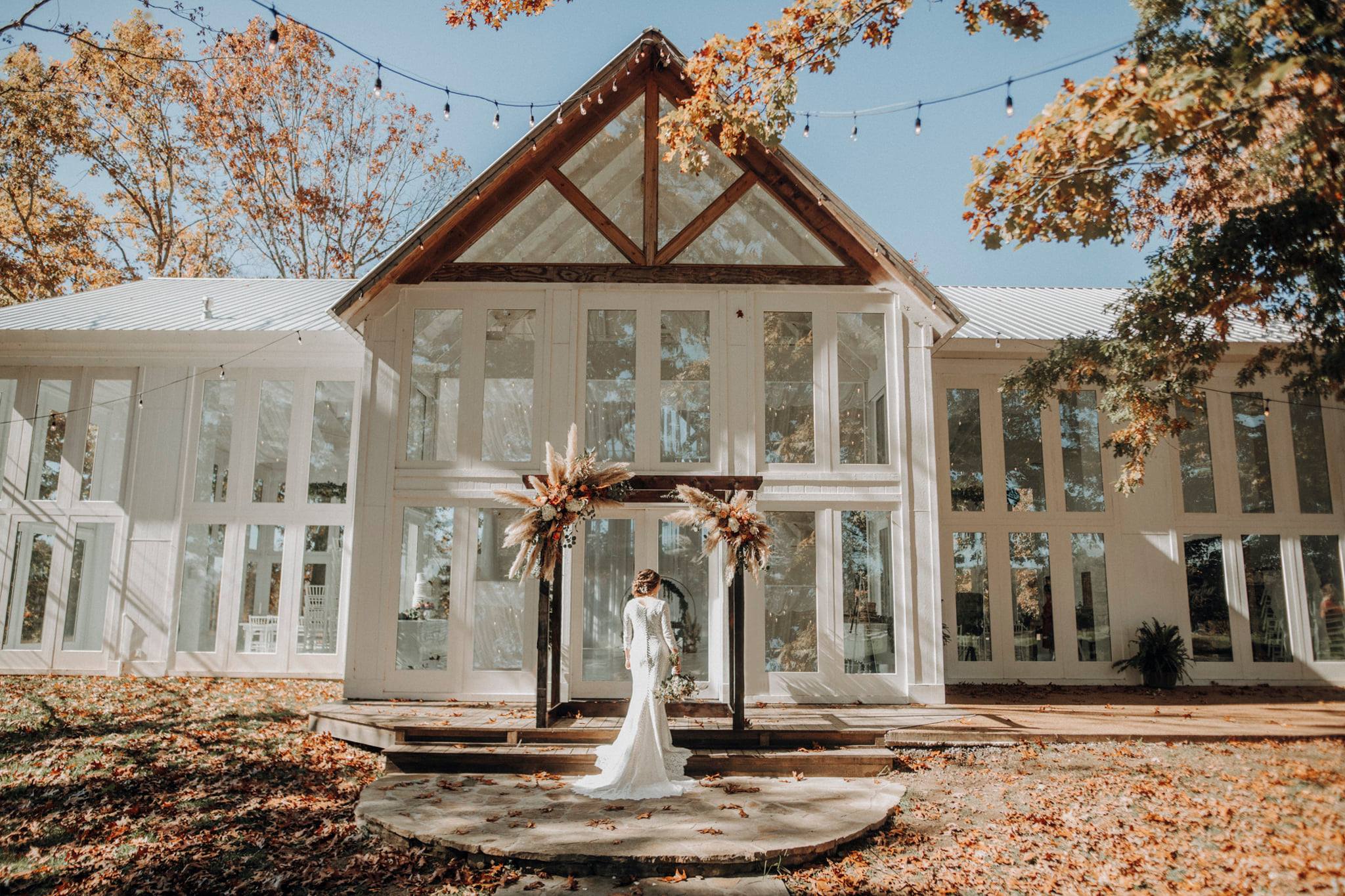 Bride standing in front of venue holding flower bouquet